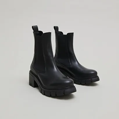 Heeled boots with notched soles in black leather