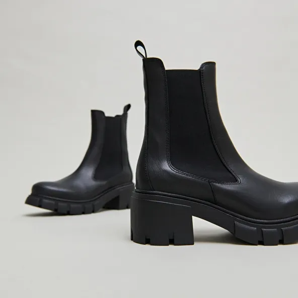 Heeled boots with notched soles in black leather